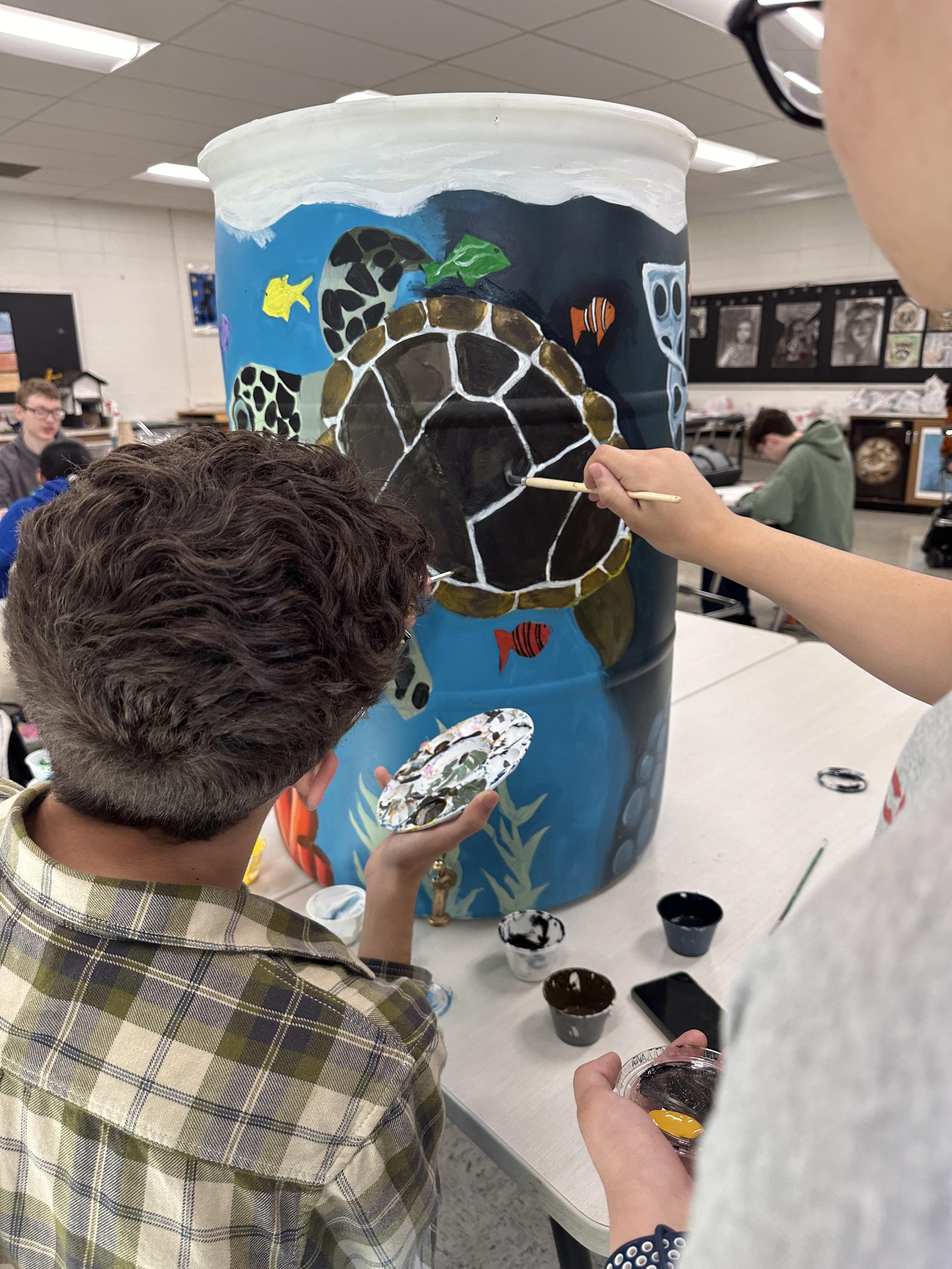 MHS students paint a rain barrel for the city's Earth Day raffle